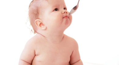 Baby feeding using spoon on white background